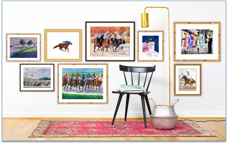 May include: A collection of framed watercolor paintings depicting horses racing, a cocktail, and a group of people. The paintings are hung on a white wall with a black chair and a silver basket in the foreground.