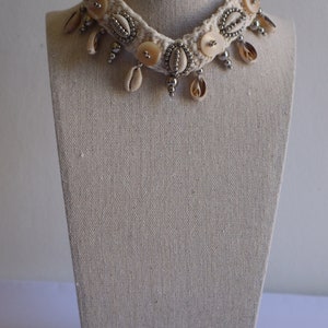 K&ouml;nnte beinhalten: Eine wei&szlig;e geh&auml;kelte Choker-Halskette mit silbernen Perlen und Muschelakzenten.