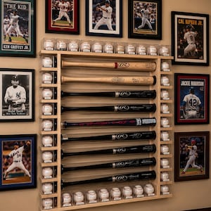 May include: A baseball-themed display featuring framed player photos, baseballs in clear cases, and baseball bats. The bats are arranged vertically, and the display includes images of Ken Griffey Jr., Babe Ruth, Cal Ripken Jr., and Jackie Robinson.