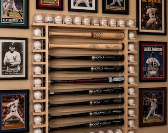 May include: A baseball-themed display featuring framed player photos, baseballs in clear cases, and baseball bats. The bats are arranged vertically, and the display includes images of Ken Griffey Jr., Babe Ruth, Cal Ripken Jr., and Jackie Robinson.