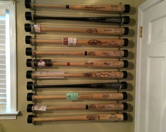 Peut inclure: Une exposition murale de battes de baseball dans des tubes en plastique transparent avec des bouchons noirs. Les battes sont signées et portent divers logos et inscriptions.