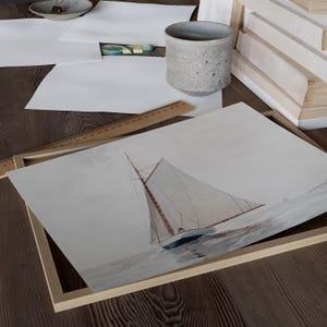 Puede incluir: Una pintura de acuarela enmarcada de un velero con velas blancas y un casco marr&oacute;n, sobre un fondo gris claro. El velero est&aacute; en el centro de la imagen y est&aacute; mirando al espectador.