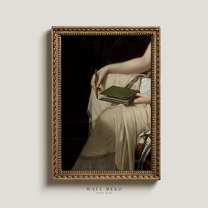 May include: A framed painting of a person holding a green book and a pen. The person is wearing a white dress and is sitting in a chair. The painting is in a gold frame.