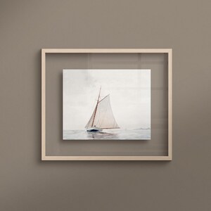 Puede incluir: Una pintura de acuarela enmarcada de un velero con velas blancas en un cuerpo de agua tranquilo. El velero est&aacute; en primer plano de la imagen, y el agua es de color azul claro. El cielo es de color gris claro, y hay algunas nubes en la distancia.