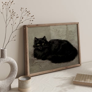 Pode incluir: Uma impress&atilde;o emoldurada de um gato preto com olhos amarelos, deitado em um fundo verde claro. O gato est&aacute; olhando diretamente para o espectador.