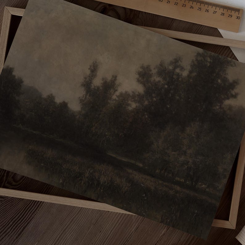 May include: A sepia-toned landscape print depicting trees and water in a dark, atmospheric scene. The artwork is framed in a light wooden frame, with a ruler visible. The vintage aesthetic creates a tranquil mood. The print is reminiscent of a classic painting.