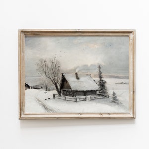 Op de afbeelding: Een ingelijst schilderij van een besneeuwde wintersc&egrave;ne met een klein houten huisje op de voorgrond. Het huisje heeft een met sneeuw bedekt dak en een schoorsteen waar rook uit komt. Er zijn bomen op de achtergrond en een pad dat naar het huisje leidt.