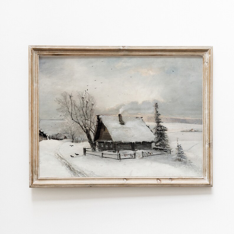 Op de afbeelding: Een ingelijst schilderij van een besneeuwde wintersc&egrave;ne met een klein houten huisje op de voorgrond. Het huisje heeft een met sneeuw bedekt dak en een schoorsteen waar rook uit komt. Er zijn bomen op de achtergrond en een pad dat naar het huisje leidt.