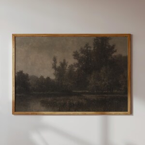 May include: A framed sepia-toned landscape painting. The artwork shows trees and water, with a muted colour palette. The painting creates a sense of calm and nostalgia, suitable for home decor. The frame is made of wood.
