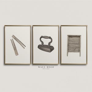 Puede incluir: Conjunto de tres grabados enmarcados con herramientas de lavandería vintage. Los grabados incluyen un par de pinzas de madera, una plancha y una tabla de lavar. Los grabados están en marcos dorados y tienen un fondo neutro. El texto "WALL DECO PRINT SHOP" está en la parte inferior.