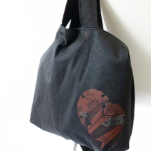 Könnte beinhalten: Eine schwarze Tragetasche mit geometrischem Muster und einem braunen Blumendesign an der Seite. Die Tasche hat zwei schwarze Henkel.