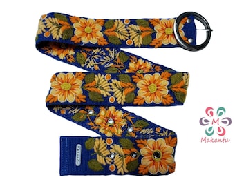 May include: A blue belt with embroidered orange and yellow flowers and green leaves. The belt has a silver-colored buckle and small silver-colored embellishments. The brand name "Makantu" is visible on the belt.