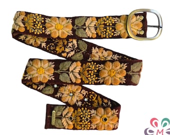 Peut inclure: Une ceinture tissée marron avec une boucle en métal doré. La ceinture est décorée de fleurs jaunes et blanches brodées.