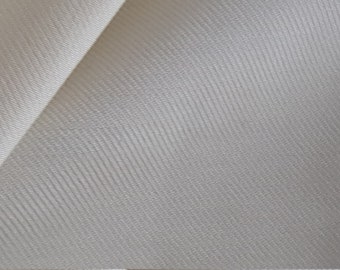 May include: Close-up of a smooth, off-white fabric with a subtle diagonal weave pattern.