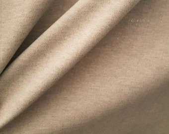 May include: Close-up of a beige fabric with a subtle textured pattern. The fabric is folded in a way that shows the texture and the light reflecting off the surface.