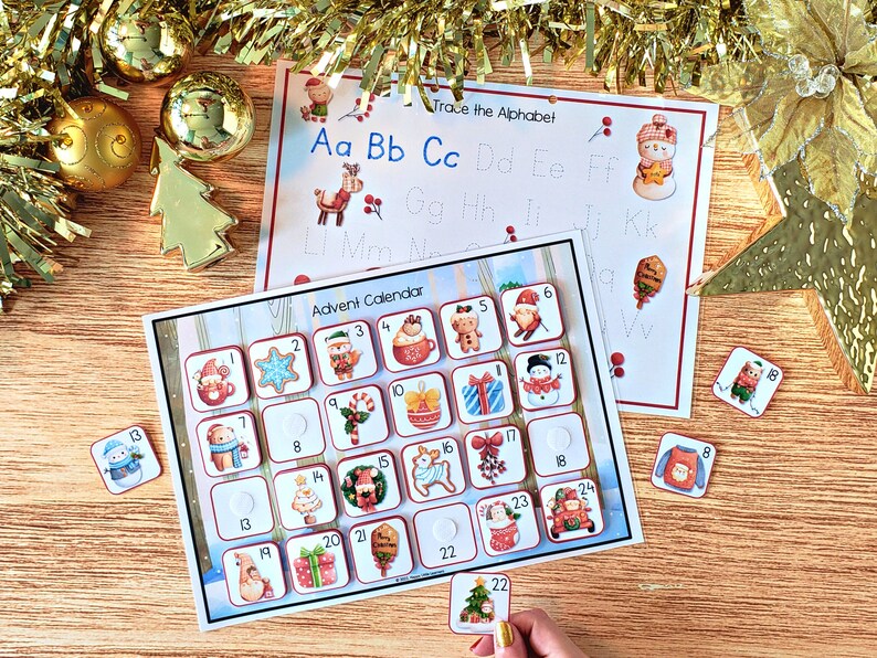 May include: A Christmas advent calendar with 24 numbered doors, each with a different festive image. The calendar is on a wooden surface with gold tinsel and ornaments.