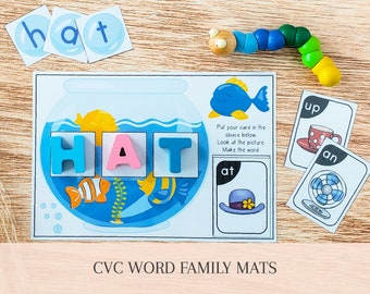 Könnte beinhalten: Eine blaue und weiße Wortfamilienmatte mit dem Wort "HAT", das in bunten Blöcken ausgeschrieben ist. Die Matte zeigt ein Bild eines Fischaquariums mit Fischen und einem Seepferdchen. Die Matte enthält auch Karten mit den Wörtern "at", "up" und "an".