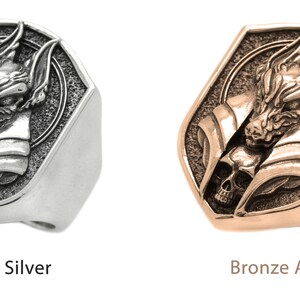 May include: A silver ring with a wolf head design and a skull. The ring is also available in a bronze alloy.