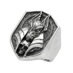 May include: A silver ring with a detailed design of a wolf's head with a skull underneath. The ring is shaped like a shield.