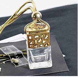 May include: Gold and clear glass car air freshener with a decorative metal cage and a gold string for hanging.