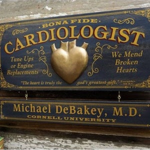 K&ouml;nnte beinhalten: Ein Vintage-Holzschild mit dem Text "Bona Fide Cardiologist" in goldenen Buchstaben. Das Schild zeigt ein goldenes Herz mit dem Text "We Mend Broken Hearts" und "Tune Ups or Engine Replacements". Das Schild enth&auml;lt auch den Text "The heart is truly the god's greatest gift." und "Michael DeBakey, M.D. Cornell University".