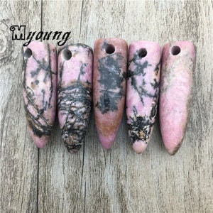 May include: Five pink and black patterned stone pendants with a hole drilled through the top. The pendants are shaped like a bullet or a teardrop.