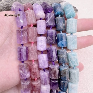 Peut inclure: Un brin de perles de pierres précieuses dans différentes nuances de violet, bleu et vert. Les perles sont cylindriques et ont une finition lisse et polie. Les perles sont enfilées sur un cordon élastique transparent.