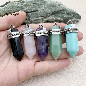May include: Five gemstone pendants in black, pink, purple, green, and turquoise. Each pendant has a silver-coloured cap and a loop for a chain. The pendants are held in a hand.