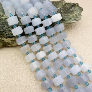 May include: A strand of light blue chalcedony beads with faceted accents. The beads are square shaped and have a smooth, polished finish.