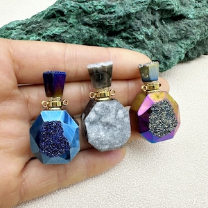 May include: Three iridescent gemstone perfume bottles with gold caps and a faceted design. The bottles are in shades of blue, gray, and purple.