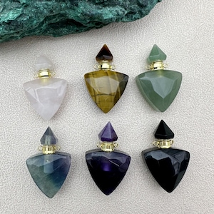 Pode incluir: Seis frascos de perfume triangulares de cristal com tampas douradas. Os frascos são feitos de quartzo rosa, olho de tigre, aventurina, ametista, fluorita e obsidiana negra.