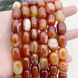 Può includere: Una collana di perle di corniola con una miscela di colori arancio e bianco. Le perle sono lisce e lucidate, con un aspetto naturale e organico.