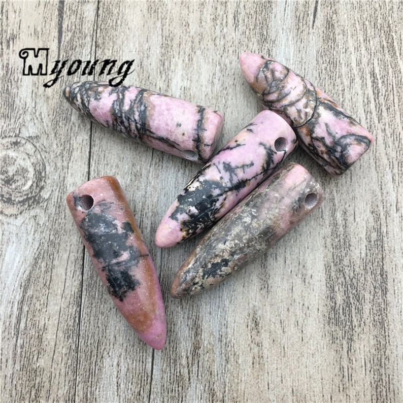 May include: Five pink and black striped, pointed, stone pendants with a hole drilled through the top for stringing.