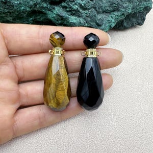 May include: Two gemstone perfume bottles with gold caps. One bottle is black and the other is tiger's eye.