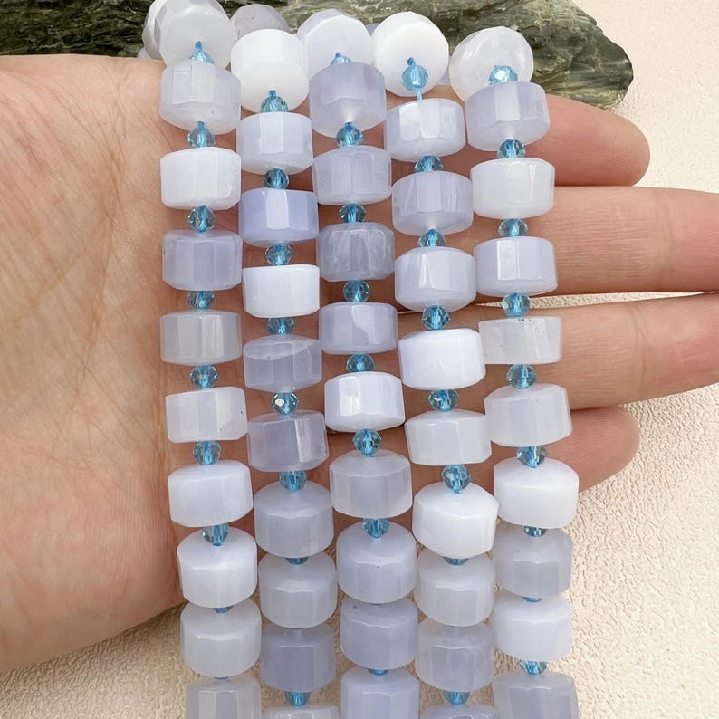 May include: A strand of light blue and white gemstone beads with faceted crystal spacers. The beads are round and have a smooth, polished finish.