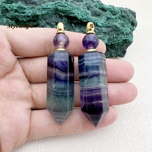 Peut inclure: Deux bouchons de bouteille en cristal de fluorine violet, vert et bleu avec des bouchons et des anneaux dorés. Les bouchons sont en forme de bouteille longue, mince et pointue.