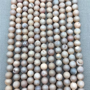 May include: A strand of light brown agate beads with a frosted finish. The beads are round and have a natural, irregular texture.