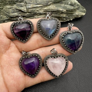 Può includere: Cinque ciondoli a forma di cuore con diverse pietre preziose colorate. I ciondoli sono in argento e hanno un design dettagliato. Le pietre preziose sono ametista, fluorite, labradorite, quarzo rosa e cianite blu.