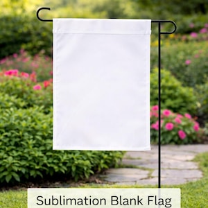 May include: A blank white flag hanging from a black metal garden stake. The flag is rectangular and has a hemmed top edge. The text "Sublimation Blank Flag Pack of 10" is displayed on a white rectangle at the bottom.