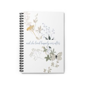 K&ouml;nnte beinhalten: Ein wei&szlig;es Spiralnotizbuch mit einem floralen Design und dem Text "and she lived happily ever after" in blauer Schrift. Die Blumen sind in Gelb-, Gr&uuml;n- und Blaut&ouml;nen gehalten.