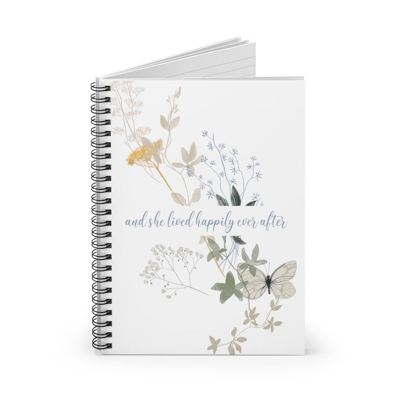 K&ouml;nnte beinhalten: Ein wei&szlig;es Notizbuch mit Spiralbindung, einem floralen Design und dem Text "and she lived happily ever after".