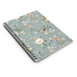 May include: A spiral bound notebook with a light blue cover featuring a floral pattern with white, pink, yellow, and orange flowers.