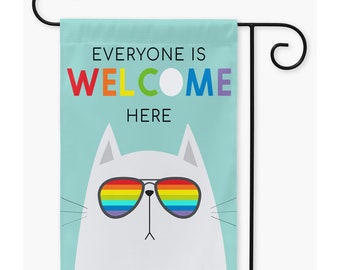 May include: A garden flag with a white cat wearing rainbow sunglasses. The flag has a light blue background with the text "Everyone is Welcome Here" in rainbow letters.