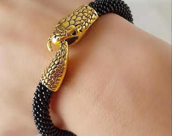 May include: A black beaded bracelet with a gold snake head clasp.