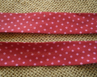 Two metres of folded bias in synthetic, red background colour with pink dots, width 21 mm