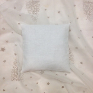Peut inclure: Un oreiller carré blanc avec une texture subtile, posé sur un tissu blanc transparent avec un motif répétitif d'étoiles et de branches.