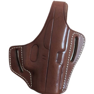 May include: A brown leather holster with white stitching. The holster has a molded design with a belt loop and two slots. The leather has a glossy finish.