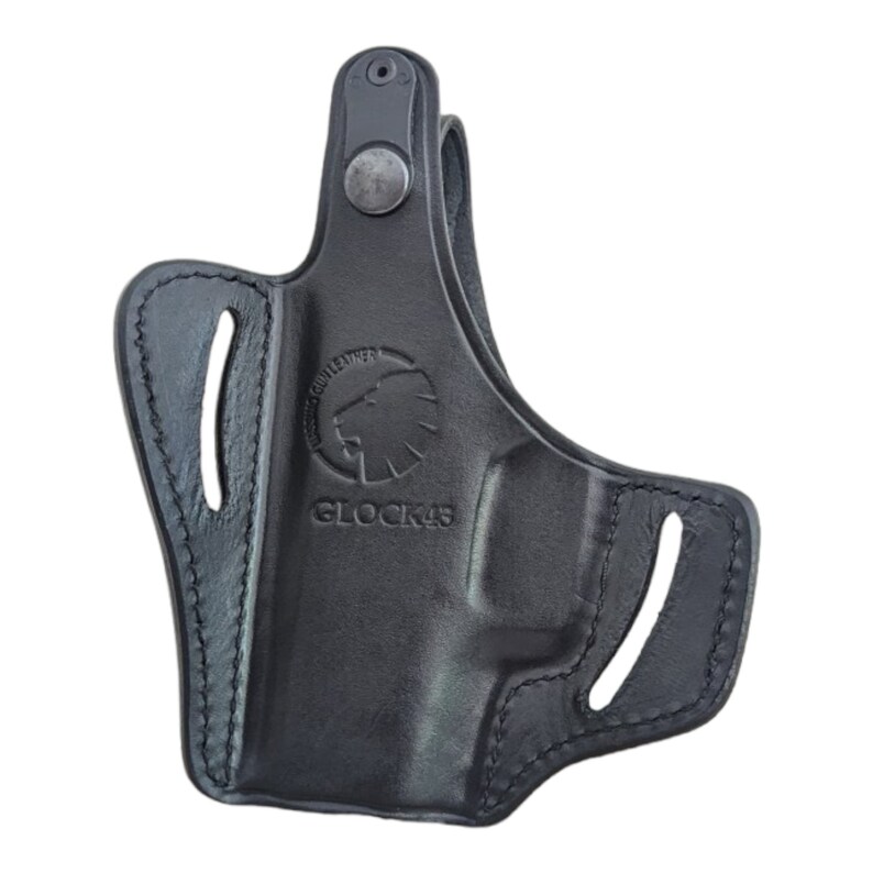 May include: Black leather holster with stitched edges. Features the text "GLOCK 43" and a lion logo. Includes a belt loop and a snap closure. Designed for a firearm.