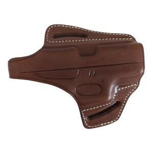 May include: A brown leather holster with white stitching. The holster has a molded design with a curved shape and two openings for a belt. The stitching is visible along the edges and around the openings.