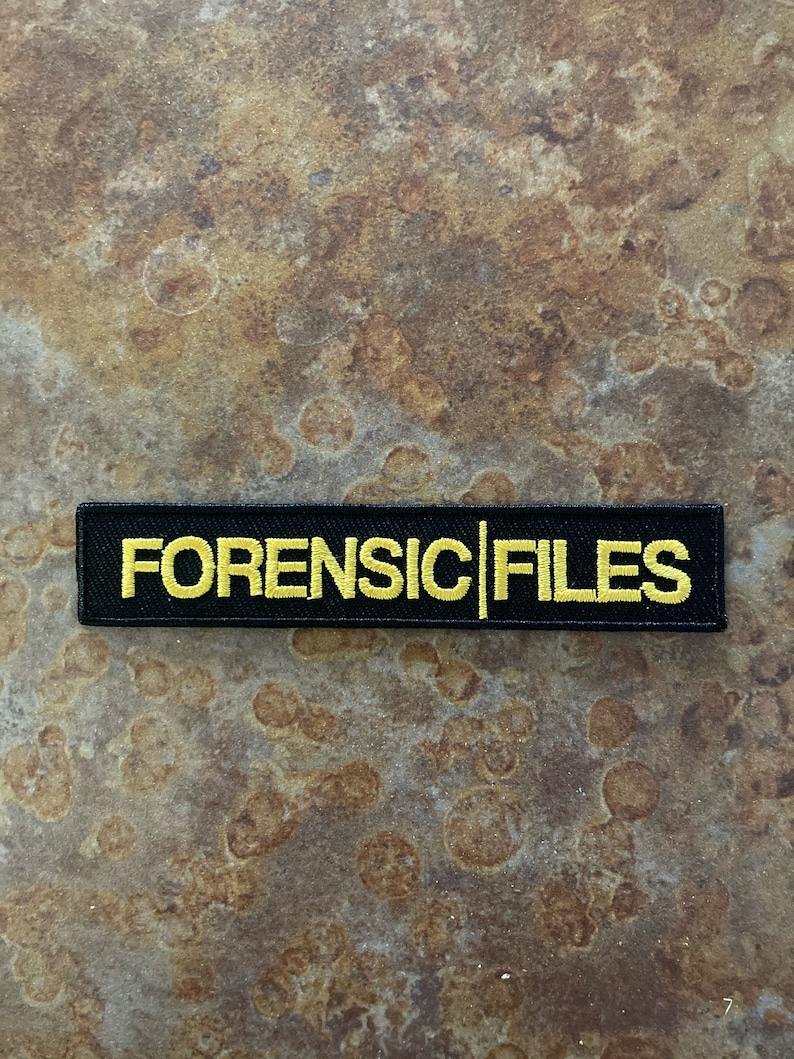 May include: Black embroidered patch with yellow stitching that reads "FORENSIC FILES".